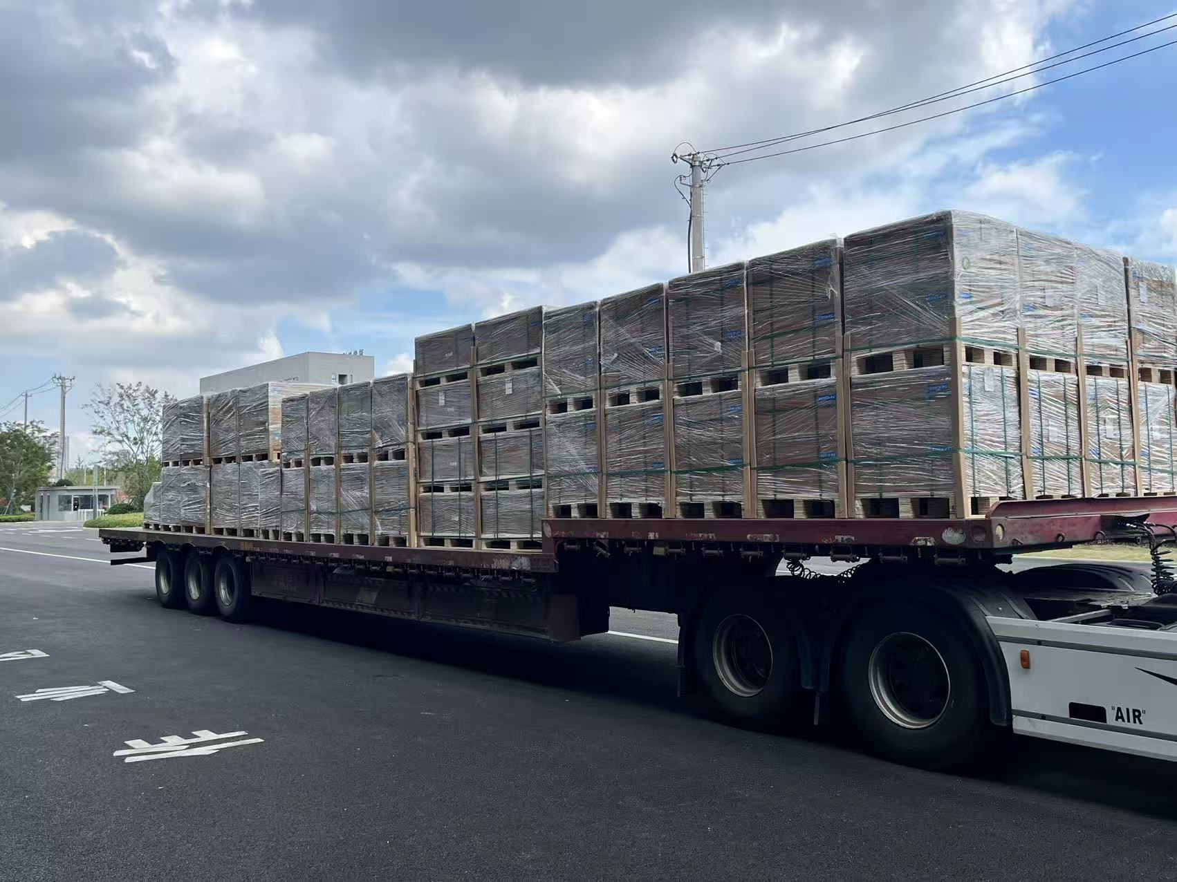 Large flatbed truck fully loaded with wrapped solar panel pallets